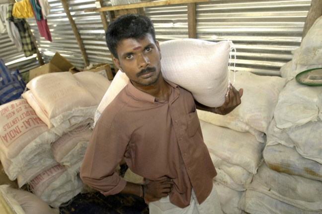 Kirubaharan carrying sacks of rice for distribution. He works for Oxfam Australia's partner KPNDU (Koralaipattu North Development Union). KPDNU is building temporary shelters and distributing food and non food items.