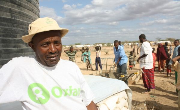 JJ Singano - a Oxfam public health engineer stands by a newly installed water tank at Dadaab refugee camp. 1400 refugees come to the camp each day and so JJ has to act fast to respond to the growing number of residents.