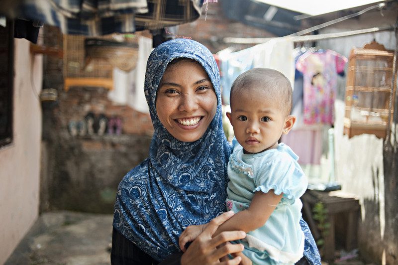 PT Panarub factory employee Lilis Suryani ad her daughter Ayu outside her rented room, Lilis, who makes shoes for adidas, pays about one-third of her salery on rent and childcare. Photo: Dave Tacon/Polaris/OxfamAUS