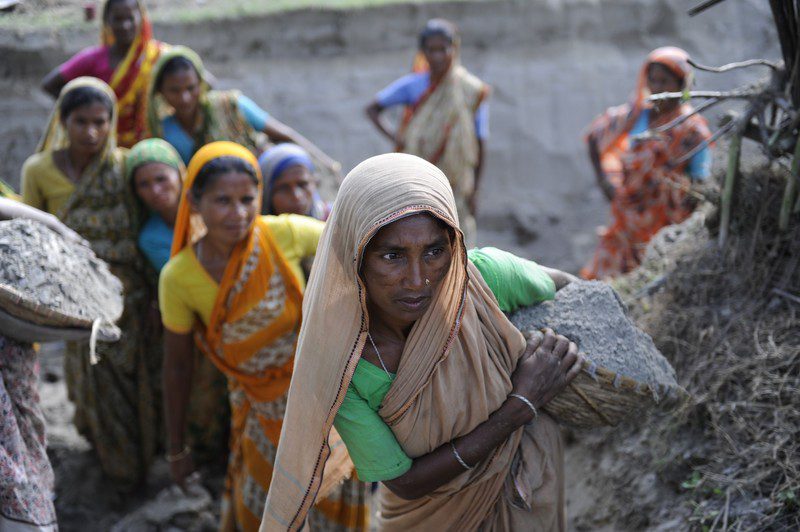 Sufia, 35, and other Bangladeshi women working as day labourers, help to raise the ground beneath her home above the flood level.