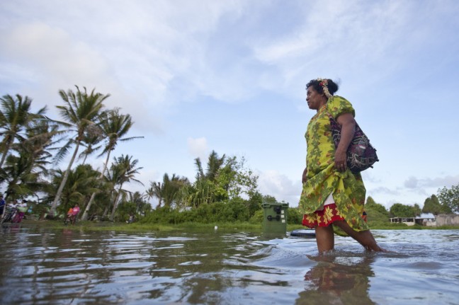 A lady walks through the king tide waters near Lotonui Community Hall, Tuvalu