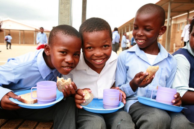 Children at Joe Slovo Junior Primary School, South Africa, are fed during lunch break by food prepared and served by Sophakama CBO volunteers, an Oxfam partner organisation. Photo: Matthew Willman/OxfamAUS