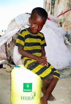 A child at the camp sits on a jerry can supplied by Oxfam. Photo: HIJRA