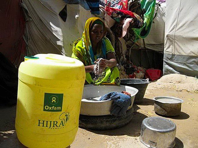 Medina washes clothes outside her makeshift shelter at the camp. Photo: HIJRA