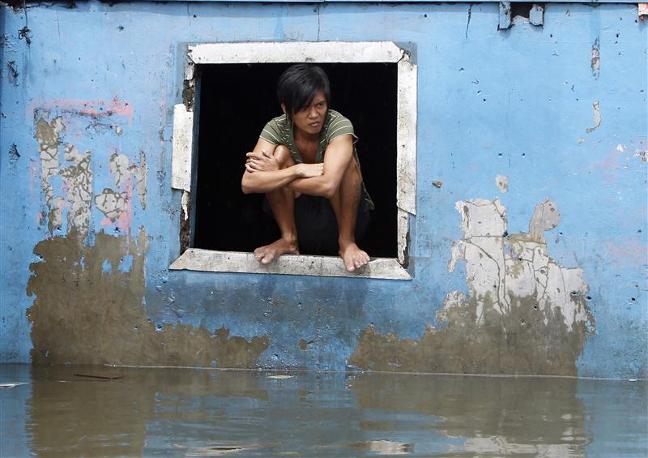 A resident sits on the window of a house swamped with floodwaters in Quezon city, Metro Manila, Philippines. Photo: Reuters/Erik de Castro