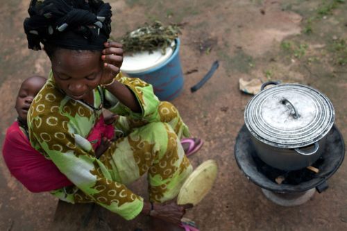 Photo: Holly Pickett/Oxfam Food vendor Dado Sade cooks the evening meal with her baby, Dauda Mballo, on her back. “If I haven’t anything for the children to eat, I go to another home and ask for food. If they have rice prepared, we give it to the children. Between the women, this is okay.” Oxfam’s cash programs are intended to provide indirect benefits to vendors like Sade, who depend on the market for their living. Photo: Holly Pickett/Oxfam
