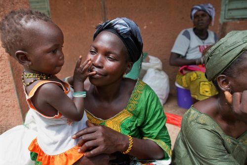 Photo: Holly Pickett/Oxfam Sira Mane takes time to connect with her child at a hygiene kit distribution in the village of Fafacourou. Photo: Holly Pickett/Oxfam