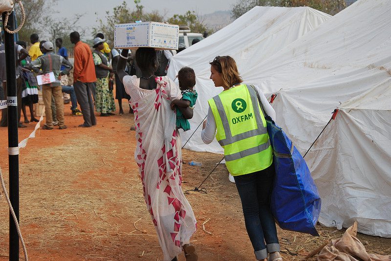 An Oxfam member of staff helps to carry one family's newly received non-food items home in UN House, Juba. Photo: Anita Kattakhuzy/ Oxfam SouthSudan