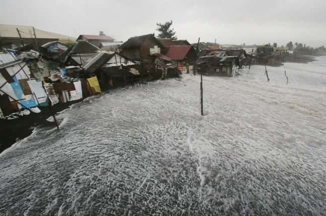 Strong waves crash into coastal houses as Typhoon Hagupit pounds Legazpi, Albay province, eastern Philippines on Sunday, Dec. 7, 2014. Photo: AP/Aaron Favila