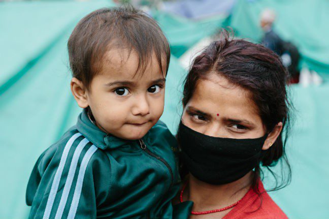 Sangita Kafle holds her son *Nabin (3) at the Tundikhel IDP camp in Kathmandu, Nepal: “My husband, my children and I are sharing a tarpaulin with 21 people. We borrowed money to pay for it…we left with nothing.” *name changed. Photo: Aubrey Wade. Nepal_response1_Aubrey Wade_648x431