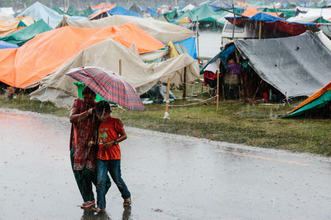 People living in temporary tents and shelters made from tarpaulin at the Tundikhel IDP camp in Kathmandu, Nepal, battle heavy afternoon rains. The start of the monsoon season is expected to hamper relief efforts. Photo: Aubrey Wade. Nepal earthquake Photo: Aubrey Wade/Oxfam