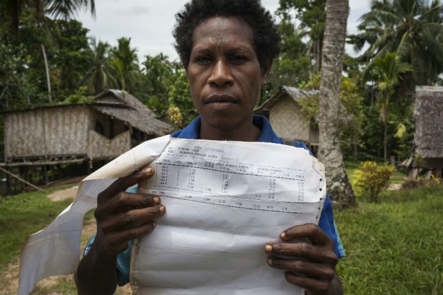Goreti Kirua from Papua New Guinea’s East Sepik region (pictured) holding payment papers she received from a logging company. “Foreigners forced us to sign consent forms; then they destroyed our forest,” says Goreti. Photo: Vlad Sokhin/OxfamAUS