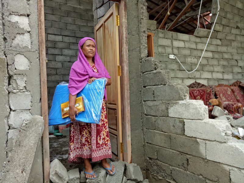Mas’ad stands outside her collapsed home near the earthquake-hit city of Palu. Mas’ad received an emergency shelter from Oxfam. Photo: Irwan Firdaus/Oxfam