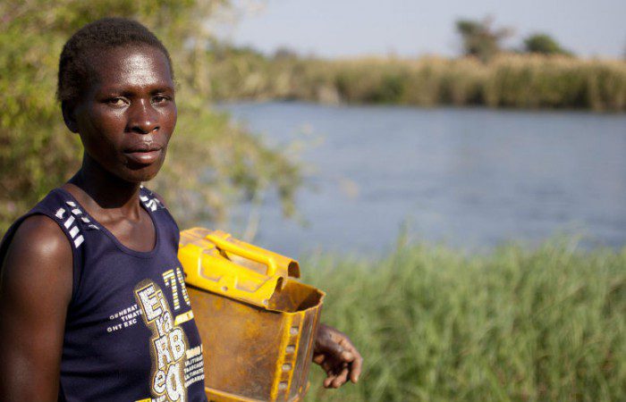 Barbara stands by the river to collect clean water. If everyone paid their fair share of tax, we could have a chance to meet the basic needs of people living in poverty, give them control over their own lives and the opportunity to change their futures.