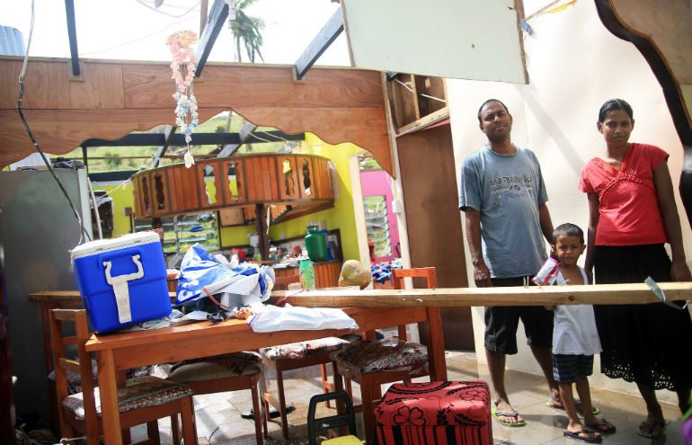 Photo: Adi Kautea Nacola/Grasskirt Photography/OxfamAUS A family stand in the remnants of their home in Fiji