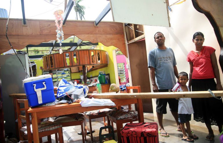 A family stand in the remnants of their home in Fiji