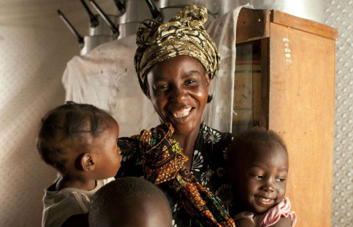 Irene smiles with holding two of her children in Zambia
