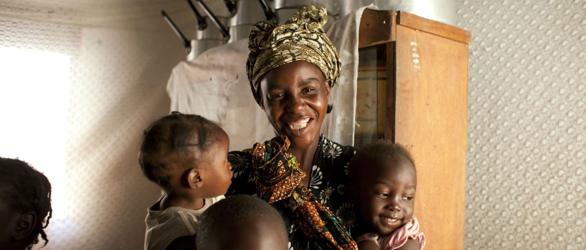 Irene smiles with holding two of her children in Zambia