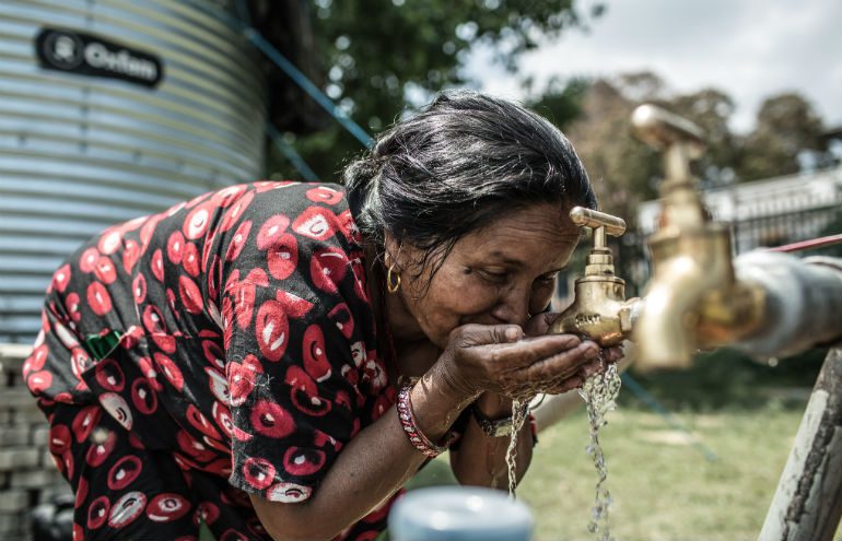 A woman drinks from a tap installed by Oxfam in the aftermath of the Nepal earthquake