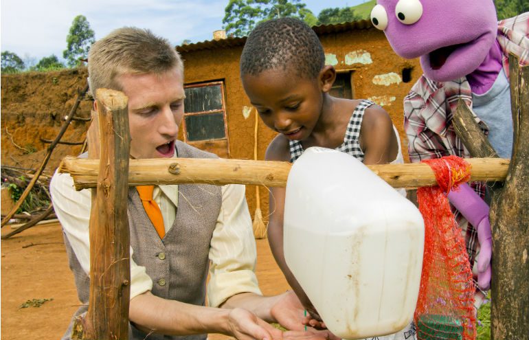 Yolanda shows Sammy J and Randy how to wash their hands properly with a tippy tap in South Africa