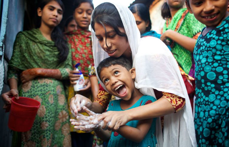 a young girl helps a boy wash his hands