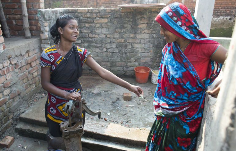 Chandra (left) shares a joke with her neighbour at the water pump outside her home
Photo: Tom Pietrasik / Oxfam Photo: Tom Pietrasik / Oxfam