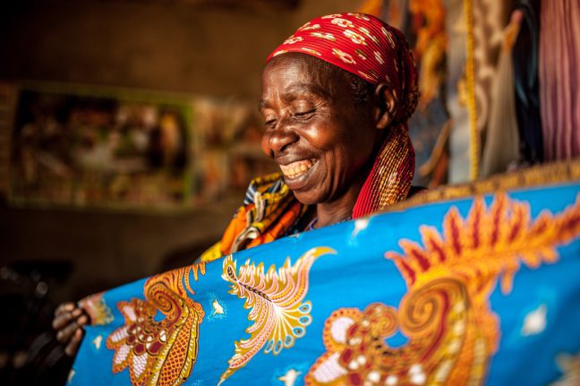 Kirehe district, Rwanda: Theresie admires tailored fabric she purchased in her home in Eastern Rwanda. Photo: Aurelie Marrier d’Unienville/Oxfam. Kirehe district, Rwanda: Theresie admires tailored fabric she purchased in her home in Eastern Rwanda. Photo: Aurelie Marrier d’Unienville/Oxfam.