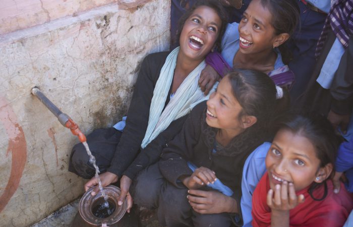 Baitadi, Nepal: Students pose for pictures with their recently installed tap stand, which was installed by Oxfam at their school in Baitadi.