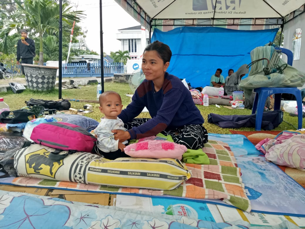 28-year-old Iren takes care her 7-month-old baby. Iren, a mother of two, has spent six nights in this tent at an IDP compound. Iren's house collapsed during the earthquake in Indonesia.