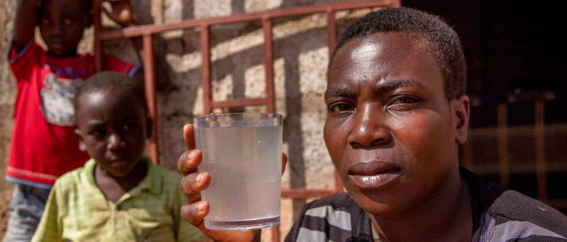 Priscilla holds a glass of dirty water in Lusaka, Zambia