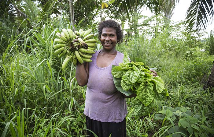 July Gede, 31, holding bananas and cabbage that she collected from her new garden. Her old garden was destroyed by 2014 floods.