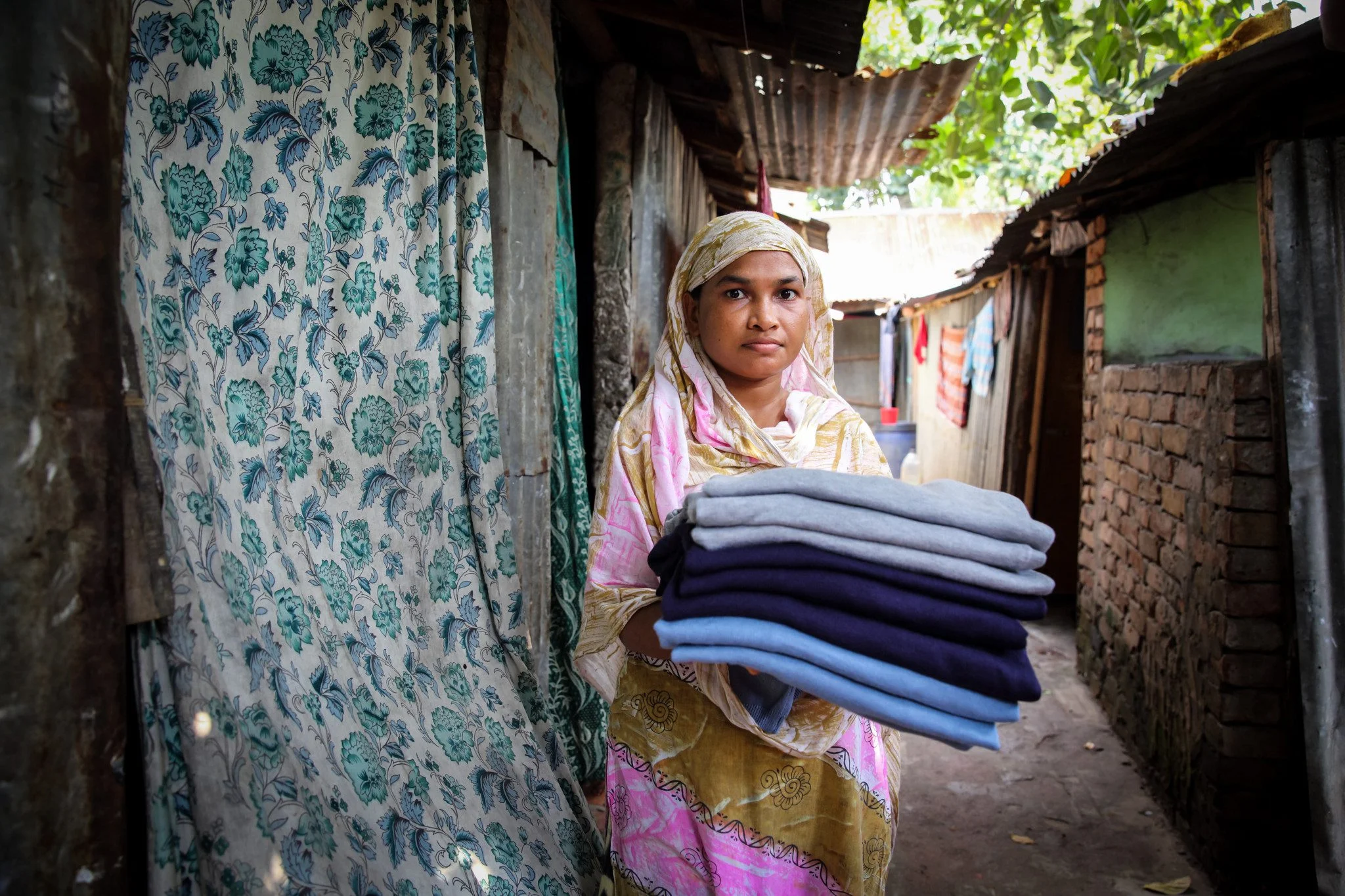 , Anju (25) holds sweaters made in Bangladesh for an international brand. Dhaka, Bangladesh