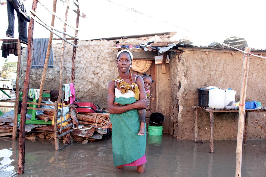 Ester stands with her three year old child in front of her damaged home in Mozambique following Cyclone Idai’s destruction. Image: Tina Kruger/Oxfam