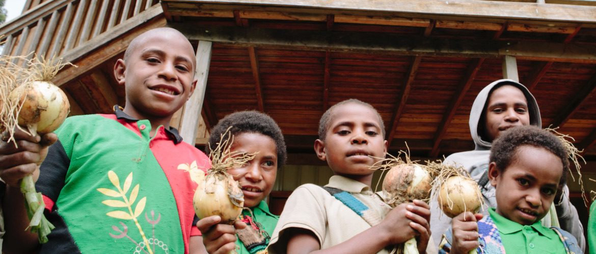 Children hold onions outside their school building