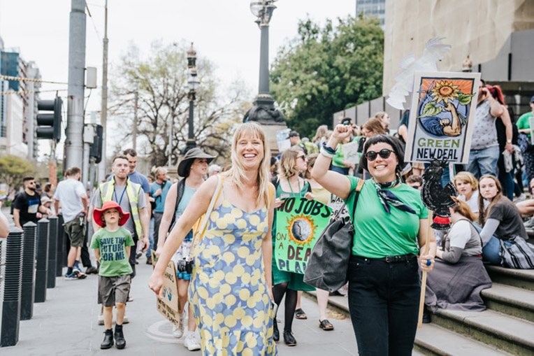 Oxfam staff protesting in Melbourne with big smiles and colourful signs.