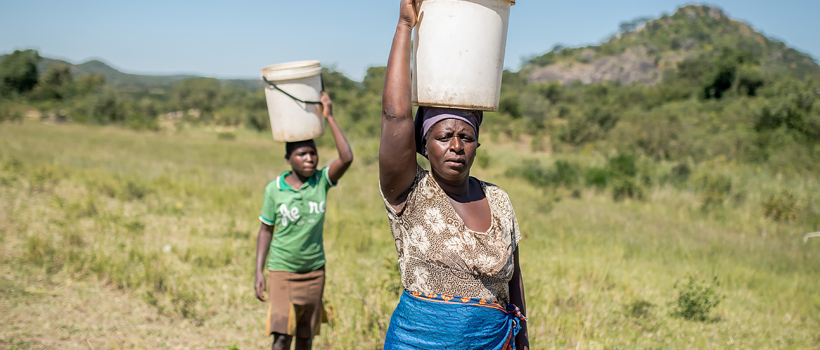 Enya collecting water with her child