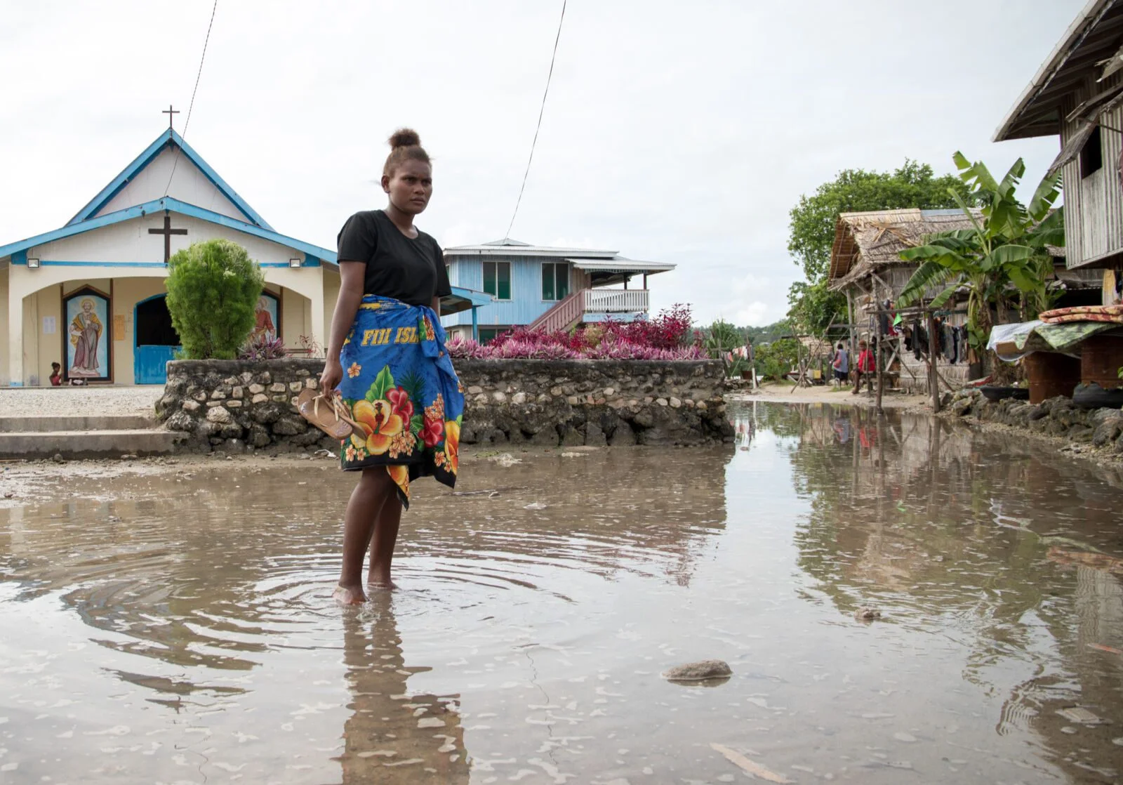 Lilisiana, Malaita Province, Solomon Islands: Grace Namoi (19), a student at the local high school, walks through water left in the town square after a high tide. Grace worries about the future of her town with the visible impacts of a changing climate.