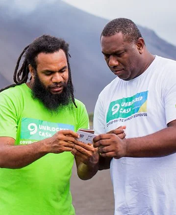 Tanna, Vanuatu: Keith and Sirus test cards and phones in prep for beneficiary registrations. Unblocked cash transfer program role out in Tanna Vanuatu. response. Photo: Arlene Bax/Oxfam in Vanuatu Tanna, Vanuatu: Keith and Sirus test cards and phones in prep for beneficiary registrations. Unblocked cash transfer program role out in Tanna Vanuatu. response. Photo: Arlene Bax/Oxfam in Vanuatu