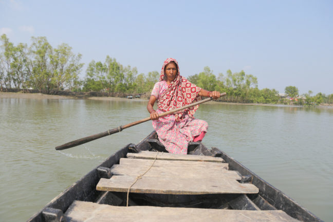 A woman rows a boat over a swelling river