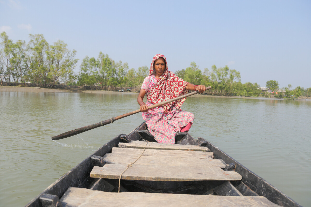 A woman rows a boat over a swelling river