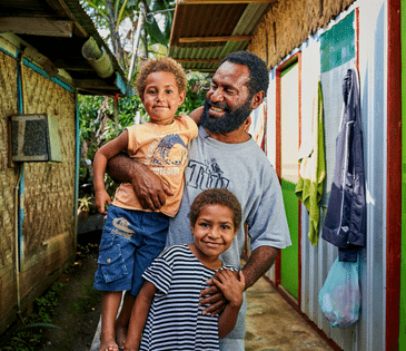 Goroka, Papua New Guinea: Yoma Barile, a youth leader in Goroka LLG, with his children Alina* and Ive* outside their home.