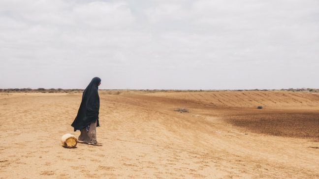 Diyaara stands before a dried water hole. Photo: Khadija Farah/Oxfam