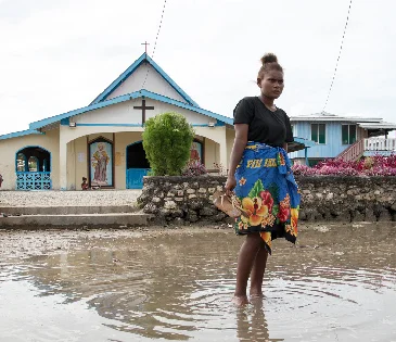 Lilisiana, Malaita Province, Solomon Islands: Grace Namoi (19), a student at the local high school, walks through water left in the town square after a high tide. Grace worries about the future of her town with the visible impacts of a changing climate.