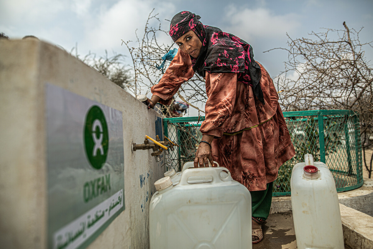 Samiha Ali recoge agua en un bidón en un punto de distribución construido por Oxfam. Amina huyó junto a sus hijos cuando el conflicto llegó a la gobernación de Tahiz. Sin poder recoger nada de su hogar buscaron refugio en el Campo de personas desplazadas de Al Bearrayer, Al Thurba, Gobernación de Taiz. En el campo de desplazados de Al Bearrayer viven cerca de 1.000 persona que huyeron del conflicto, mayoritariamente de la zona sur y centro-sur, de la misma gobernación. El frente está a una escasa media hora. En agosto de 2019 hubo varios enfrentamientos muy cerca del campo, hecho que interrumpió la ayuda humanitaria. En el último cuatrimestre de 2019, Oxfam tuvo que suspender actividades en diferentes momentos.
Las tiendas y lonas se acumulan en las laderas escalonadas de la colina que conforma el asentamiento. Nos cuentan que al principio hubo problemas con las personas que ya vivían aquí porque las personas que llegaban usaban la madera y otros recursos y eso generó tensiones. Ahora cocinan con plásticos y algunas ramas.
Oxfam ha construido letrinas, distribuye kits de higiene y ha proporcionado agua a través de tanques y con camiones cisterna.
----ENGSamiha Ali collects water in a jerry can at a distribution point built by Oxfam. Samiha fled with her children when the conflict reached Taiz Governorate. They were unable to take anything from their home and sought refuge at Al Bearrayer displaced persons camp in Al Turba, Taiz Governorate.Around 1,000 people who fled the conflict, mostly from the south and centre-south of Taiz Governorate, are now living in Al Bearrayer displacement camp. The frontline is just half an hour away. In August 2019, there were various clashes very close to the camp, which interrupted the humanitarian aid. In the last quarter of 2019, Oxfam had to suspend its activities several times.
Tents and tarpaulins have amassed on the tiered slopes of the hill where the settlement has sprung up. We are told how at first there were problems with the people who already lived here because the new arrivals were using wood and other resources, which generated tensions. Now they burn plastic and a few branches for their cooking fires.
Oxfam has built latrines, distributes hygiene kits and provides water using tanks and tanker trucks. Samiha Ali collecting water. Photo: Pablo Tosco