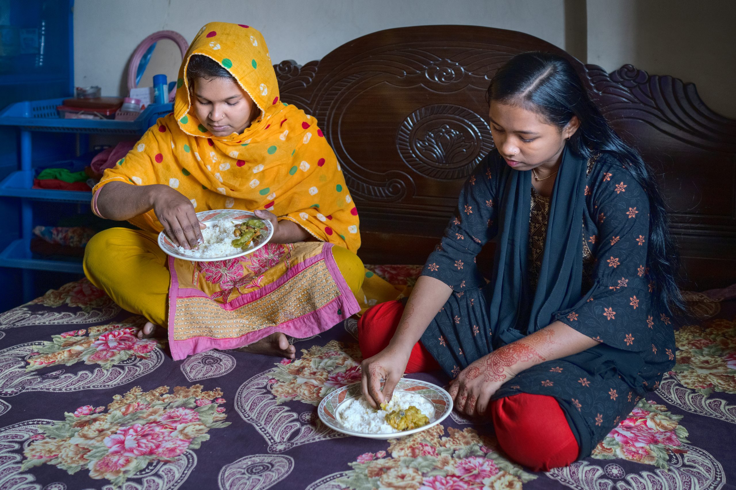 Rumi Akter having lunch with her niece. She is working as garment workers for three years now. She is living along her sister, who also works in a garment factory. As helper she fold fabrics and match them. Her target is 1440 pieces in 8 hours. With overtime she gets 10000 taka which is not enough for her living in Asulia. She can barely send money to her parents. Asulia, Bangladesh Photo: Fabeha Monir/Oxfam