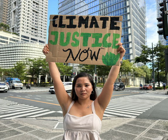 Philippines: Marinel holding placard in front of Shell HQ. Photo: Stories4Change by Climate Tracker