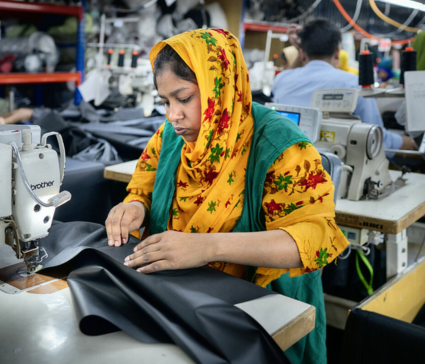 A textile worker using a sewing machine inside a factory in Bangladesh.