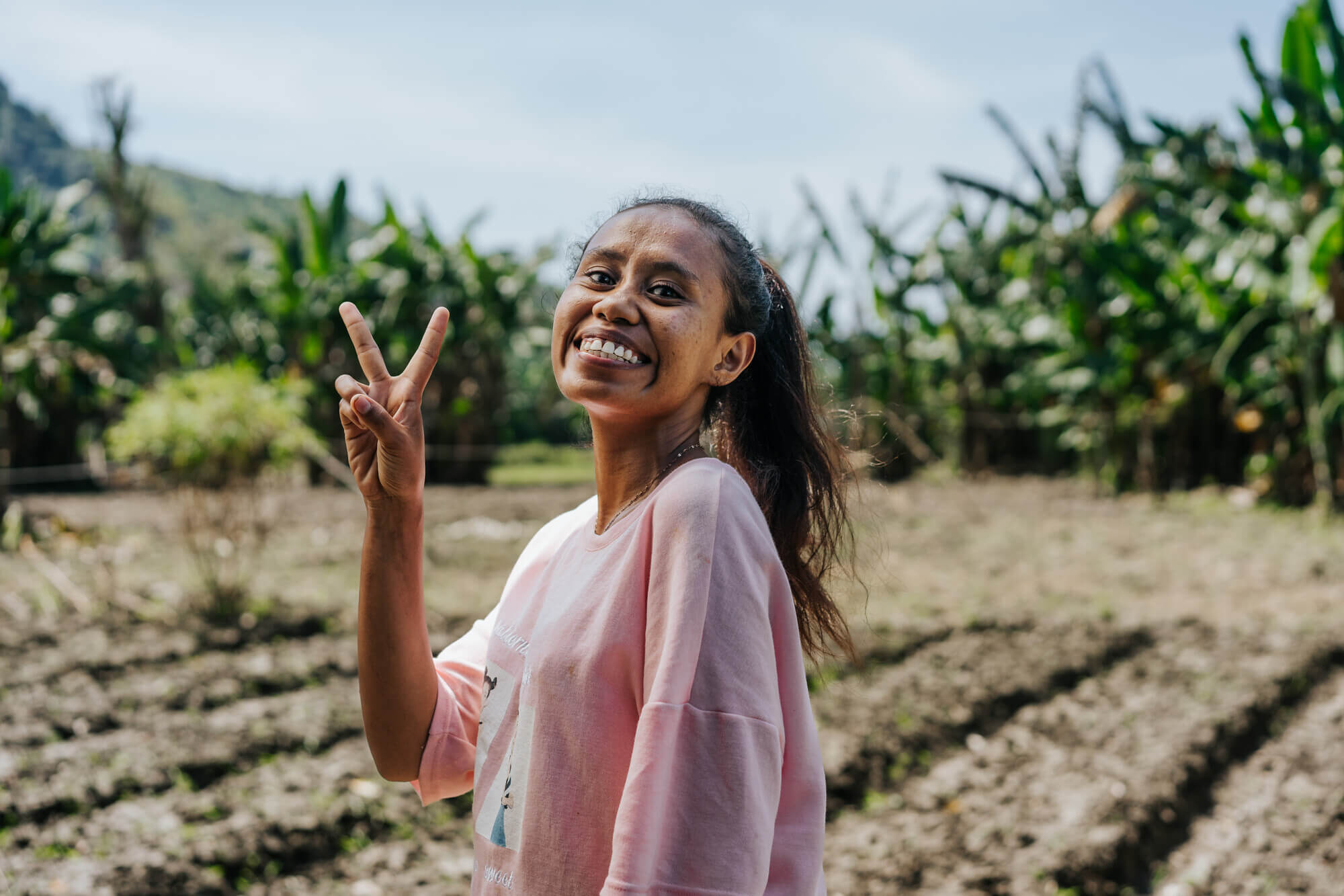 Milena smiles at the and makes a peace sign with her hands. Milena is from Youth Empowerment for Future (YEFF), who are advocating for a more diversified economy and specific budgetary support for agriculture in Timor-Leste, at their farm in Hera, outside Dili.