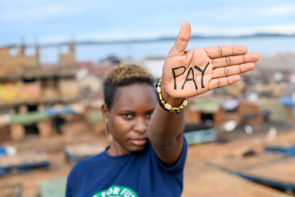 Hilda, a climate activist, holds her open palm to the camera. Her palm has 'pay' written on it. The changes to the stage-three tax cuts are a step forward, but more needs to be done to address inequality.
