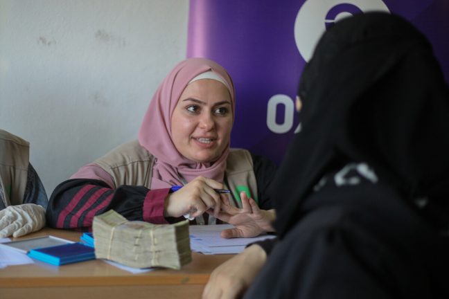 Syria: Earthquake-hit families from Aleppo in Syria receive cash from an Oxfam member to enable them to purchase what they want with dignity. Photo: Islam Mardini/ Oxfam